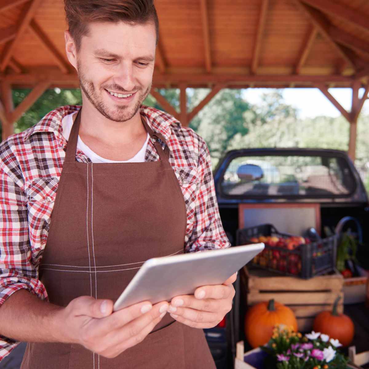 Vendedor de frutas e legumes com avental e tablet